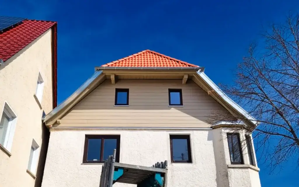 Sanierte Fassade mit horizontaler Verkleidung und rotem Ziegeldach