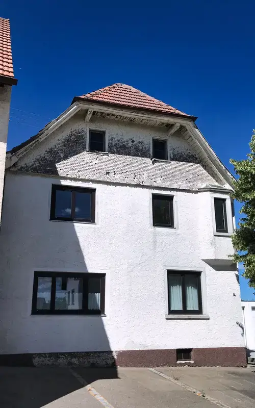Wohnhaus mit alter, weiß verputzter Fassade vor der Fassadensanierung