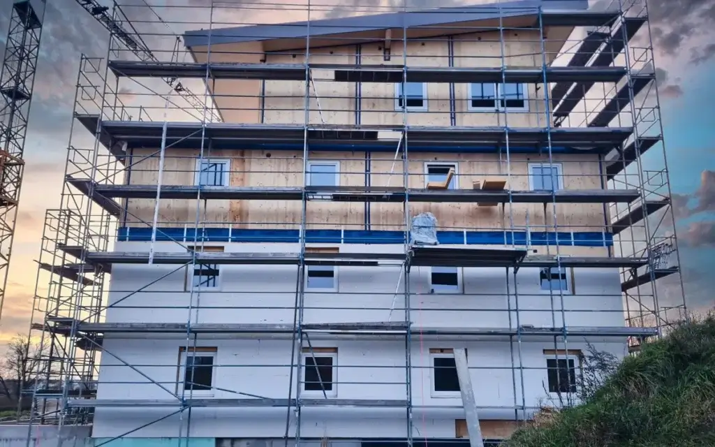 Rohbau eines mehrgeschossigen Holzhauses mit Wandelementen und Gerüst