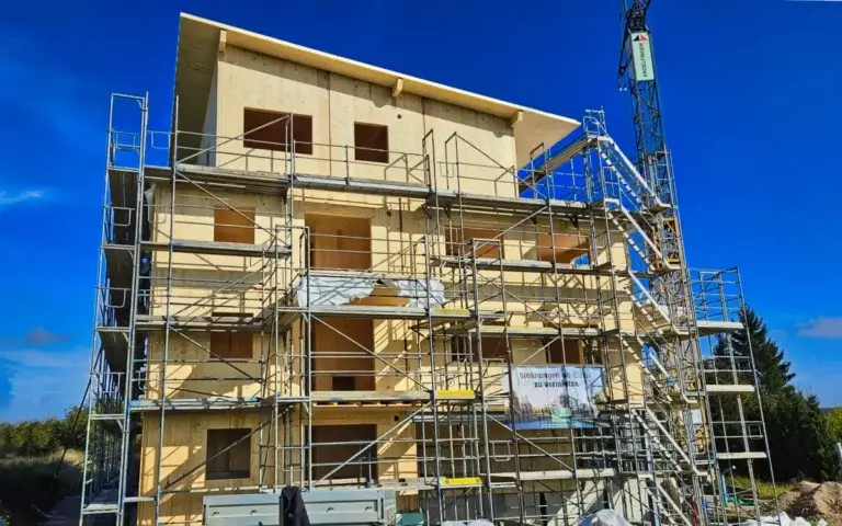 Rohbau eines mehrgeschossigen Holzhauses mit Wandelementen und Gerüst