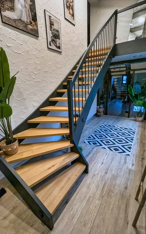 Treppe mit Holzstufen und dunklem Metallgeländer als Möbelstück im Eingangsbereich