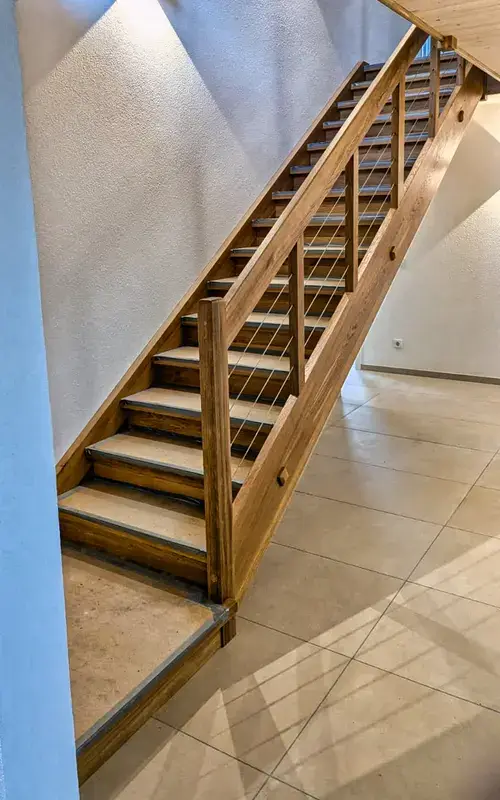 Gerade Holztreppe mit Holzgeländer in hellem Treppenhaus